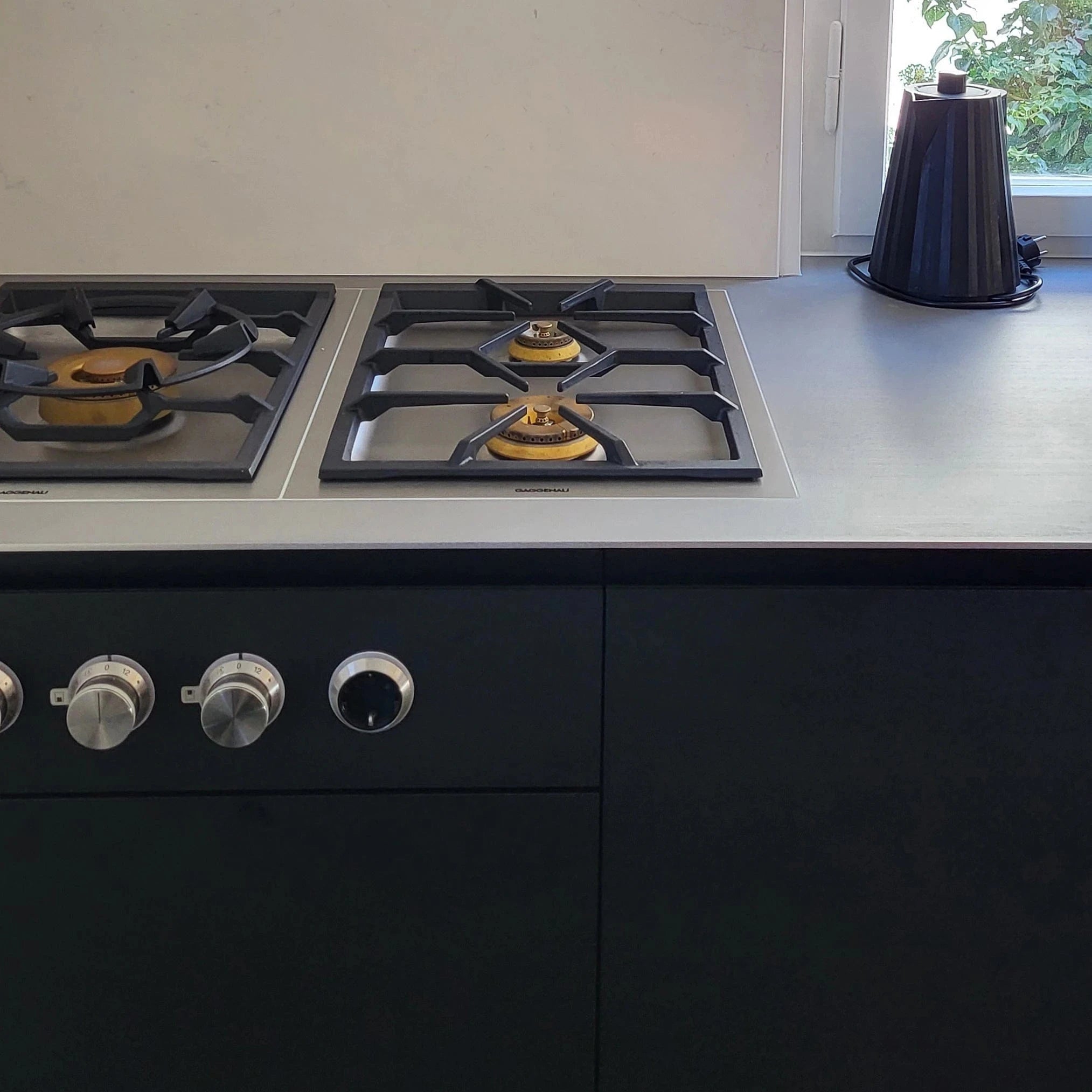 Detail Kochfeld und Fenixfront in moderner, schwarzer Küche. Küchendesign mit optimaler, individueller Raumnutzung - inspiriert durch unsere kompakte Ausstellungs-Teeküche.