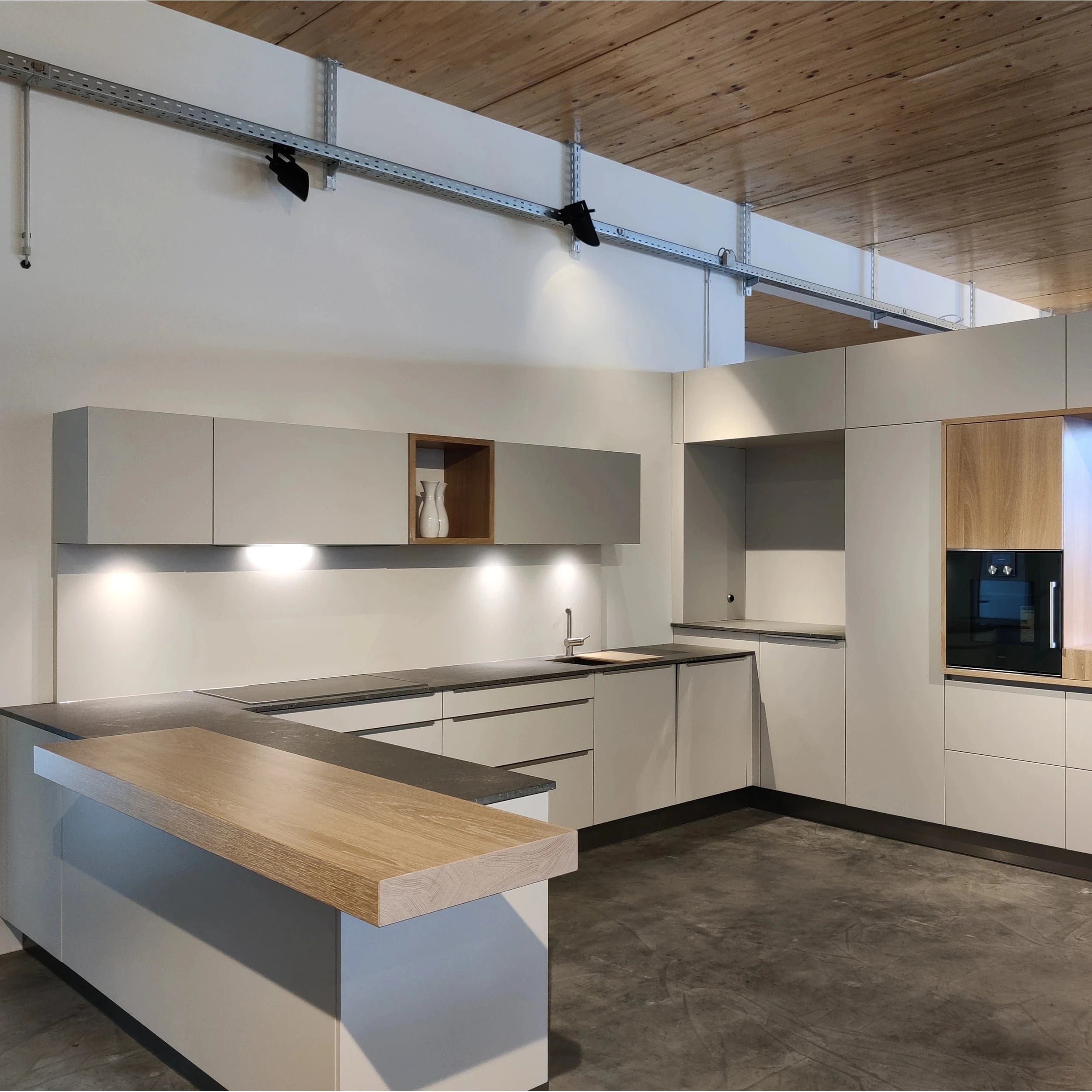 Weiße Design Küche mit Barelement in U-Form, mit Holz kombiniert in unserer Küchenausstellung in Möglingen bei Ludwigsburg & Stuttgart