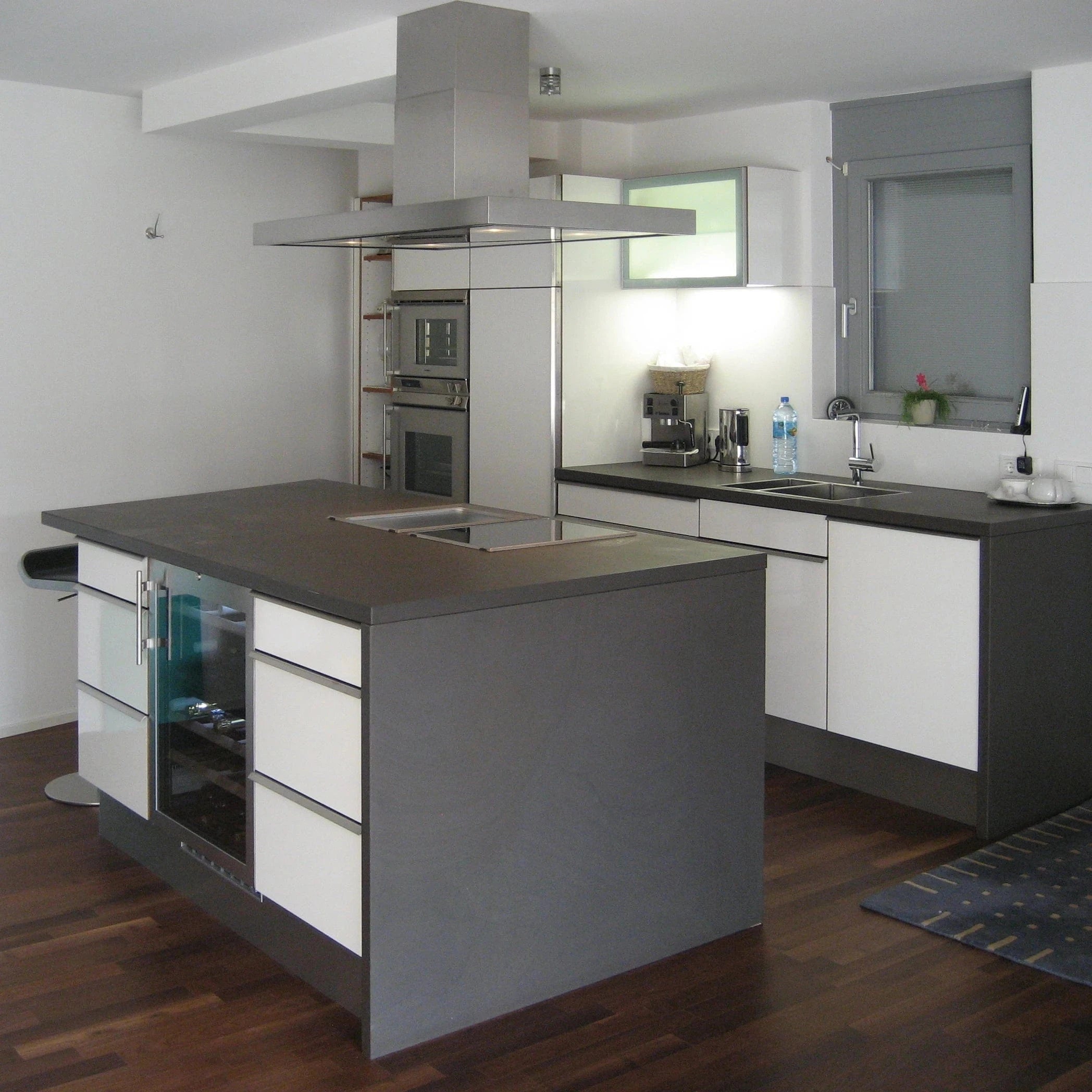 Moderne Küche mit Kochinsel aus grauem Granit, mit viel Edelstahl kombiniert.