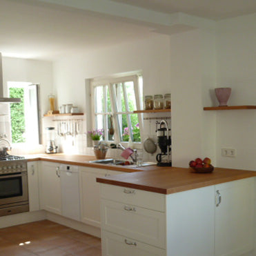 Eine Küche im Landhausstil mit weißer Front kombiniert mit einer Arbeitsplatte aus Buche Massivholz