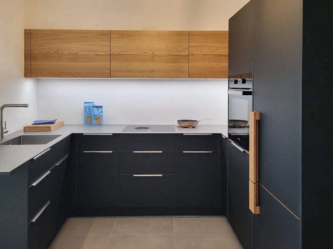 Eine ausgefallene kleine Küche in U-Form. Schwarzes Fenix kombiniert mit massivem Wildeiche-Holz und grauer Keramik-Arbeitsplatte von Dekton.