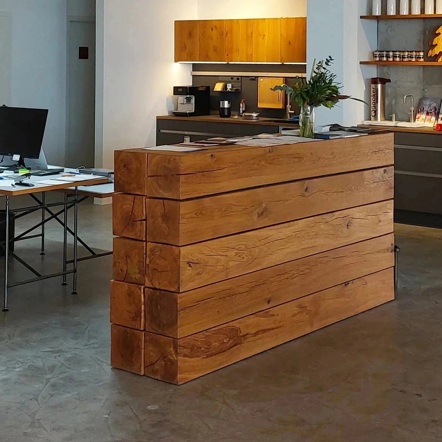 Empfangstheke in einem Verkaufsraum. Massive Eichenbalken verbergen Schubladen und Stauraum.