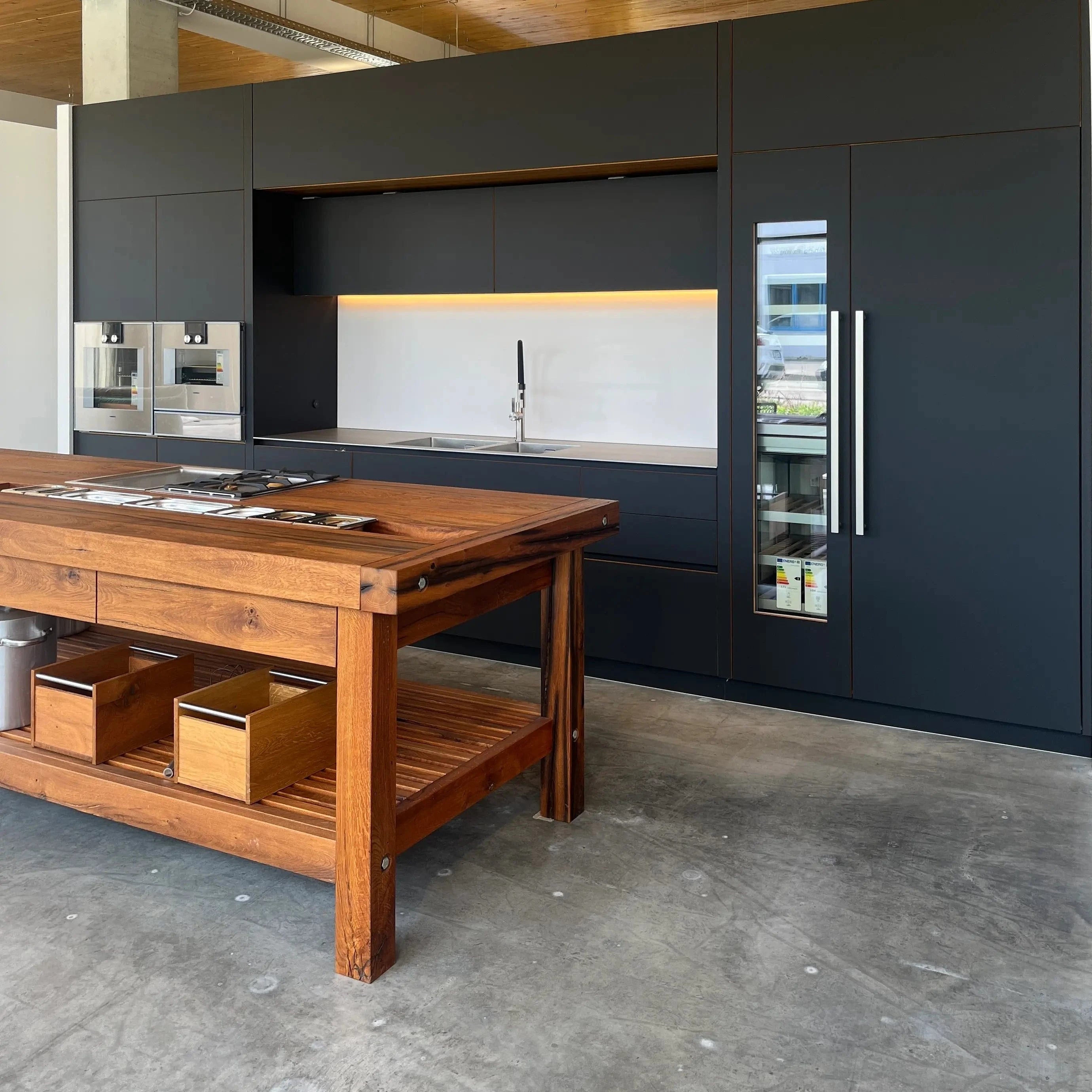 Unsere schwarze Luxus Küche steht im Zentrum unseres Küchenstudios bei Stuttgart. Eine Mischung aus goldbrauner Eiche und matten Fenix-Oberflächen vermitteln Eleganz und die Hochwertigkeit der Materialien.