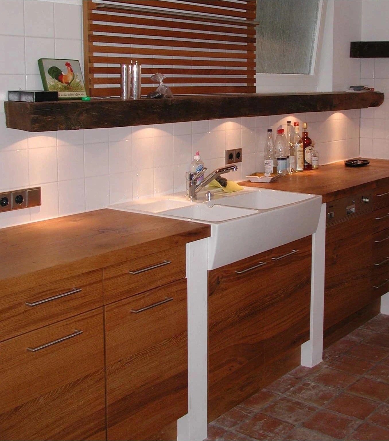 Holzküche im Landhausstil aus Kernbuche mit großem, weißem  Waschtrog auf Boden mit alten roten Fliesen.