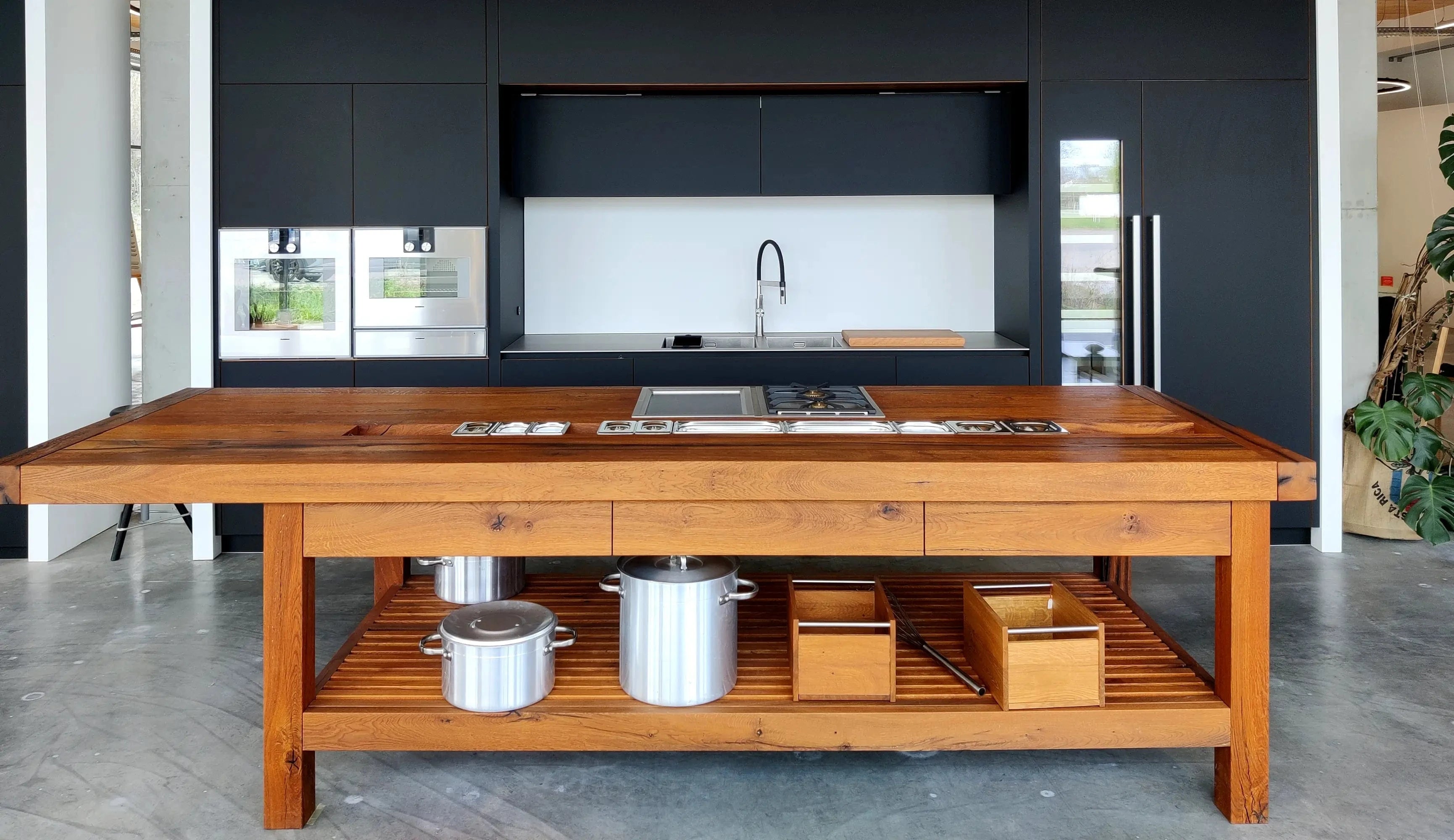 Schwarze Küche mit einer Kücheninsel aus Eiche Altholz im Küchenstudio der Schreinerei Holzmanufaktur - Die Stuttgarter Küche
