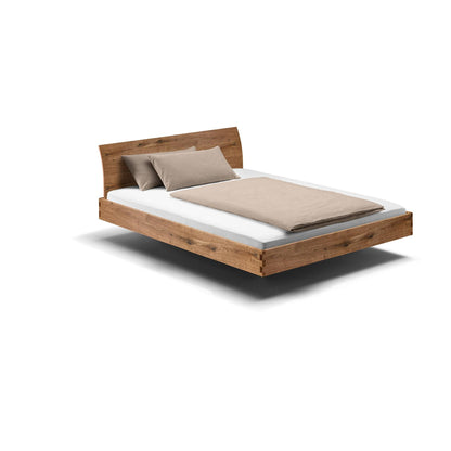 Holzmanufaktur Massivholzbett, ein hochwertiges schwebend leichtes Bett aus Wildeiche mit gebogener Rückenlehne.